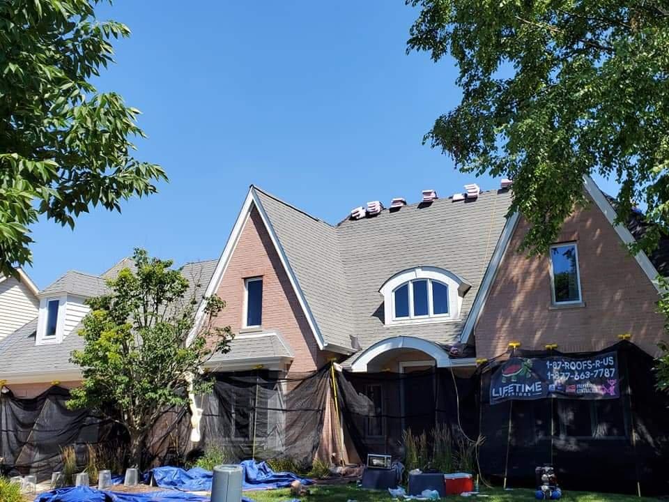 Downers Grove roofing contractors Lifetime Xteriors protect house with netting and tarps before work begins.