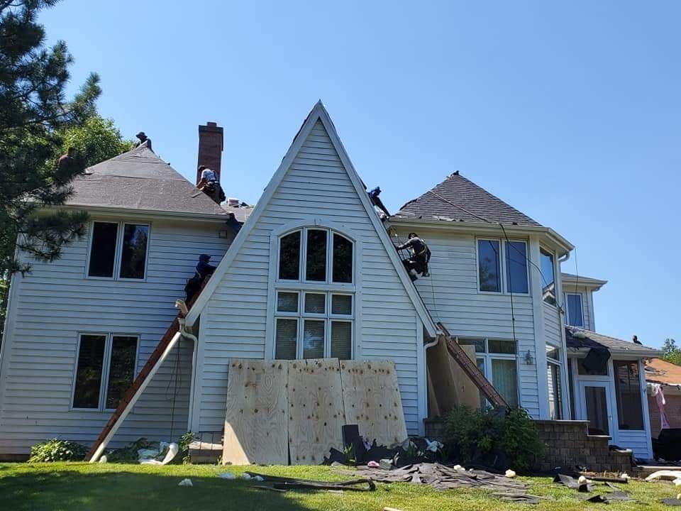 Downers Grove roofing contractors demo the old shingles.  The house is protected with plywood.  Ropes and harnesses should always be utilized by roofing companies like Lifetime Xteriors when doing a roof replacement.